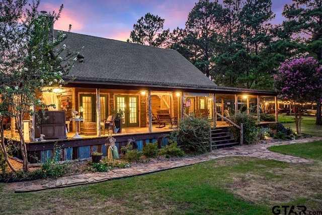 back house at dusk with french doors and a yard