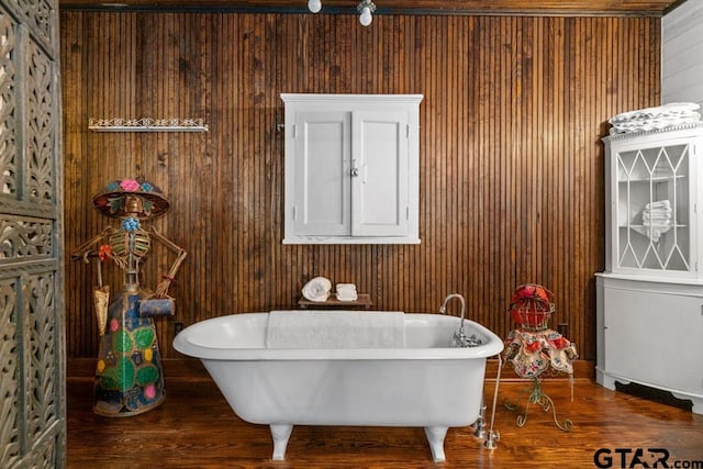 bathroom with wood-type flooring, a bathtub, and wooden walls