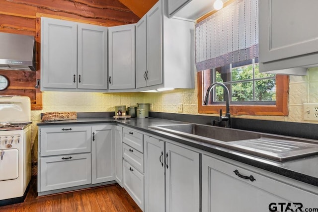 kitchen with white cabinets, sink, vaulted ceiling, light wood-type flooring, and washer / dryer