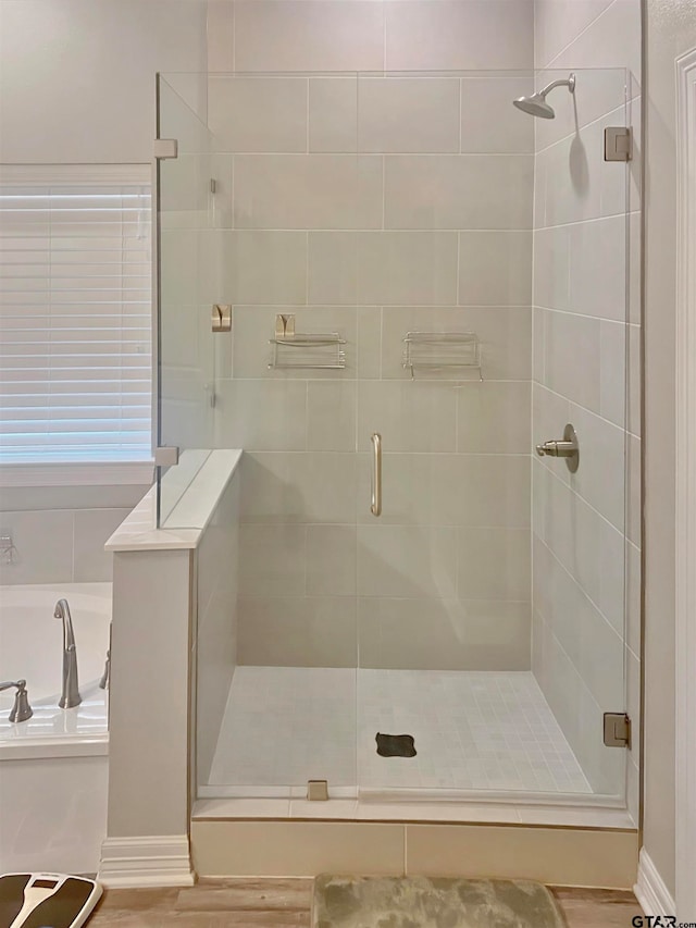 bathroom with hardwood / wood-style flooring and shower with separate bathtub