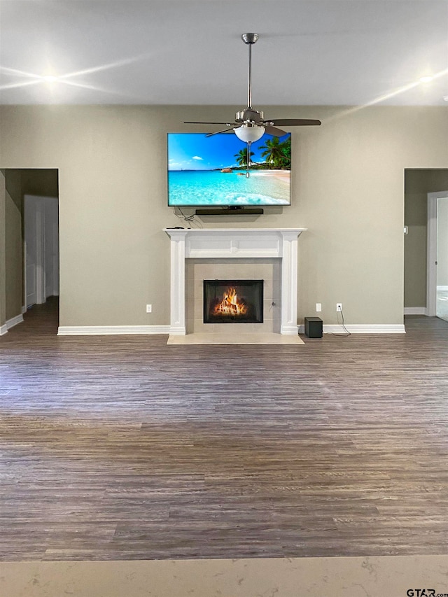 unfurnished living room with hardwood / wood-style floors, a tile fireplace, and ceiling fan