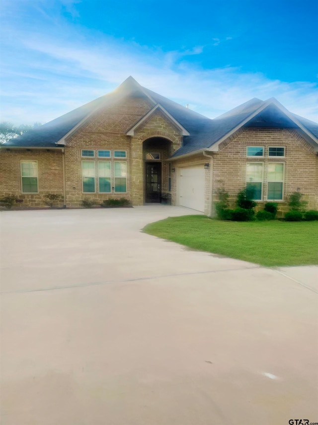 single story home featuring a garage and a front lawn