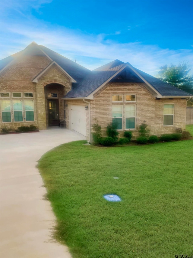 ranch-style house featuring a garage and a front lawn