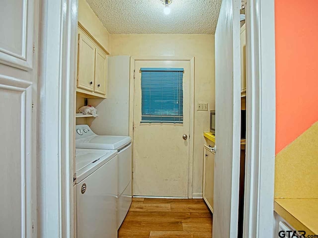 laundry area with light wood-type flooring, cabinets, a textured ceiling, and washing machine and dryer