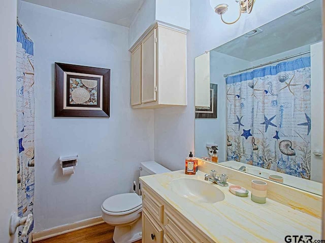 bathroom with toilet, vanity, and hardwood / wood-style flooring