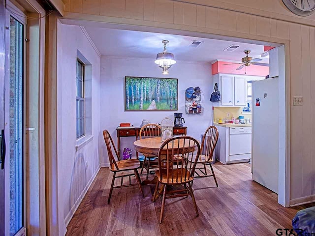 dining space with ornamental molding, light hardwood / wood-style floors, and ceiling fan with notable chandelier