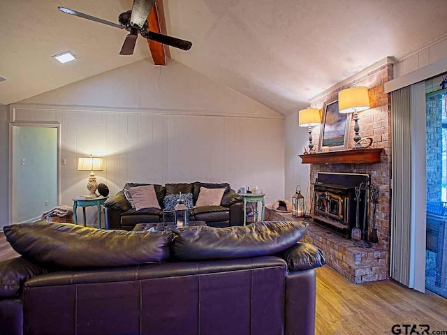 living room featuring light wood-type flooring, a fireplace, lofted ceiling with beams, and ceiling fan