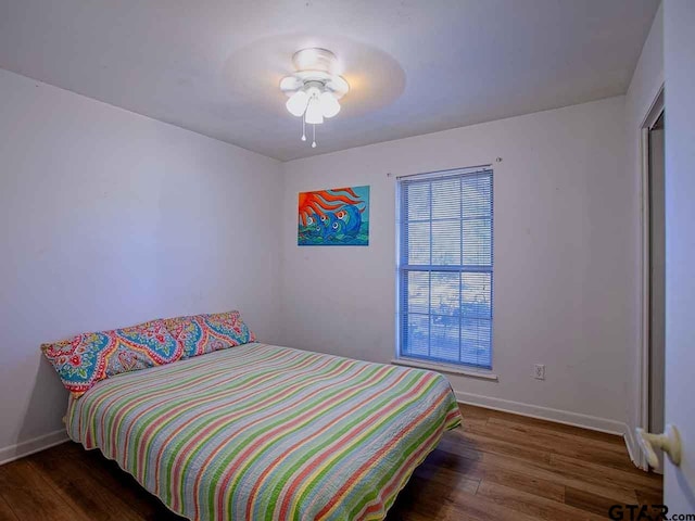 bedroom with dark hardwood / wood-style flooring and ceiling fan