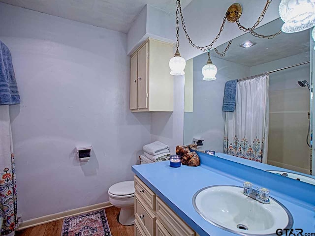 bathroom featuring walk in shower, wood-type flooring, vanity, and toilet