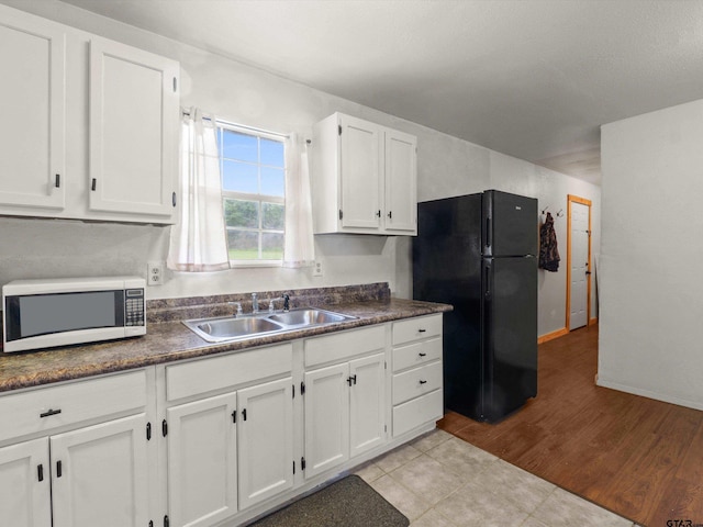 kitchen featuring freestanding refrigerator, dark countertops, white microwave, and a sink