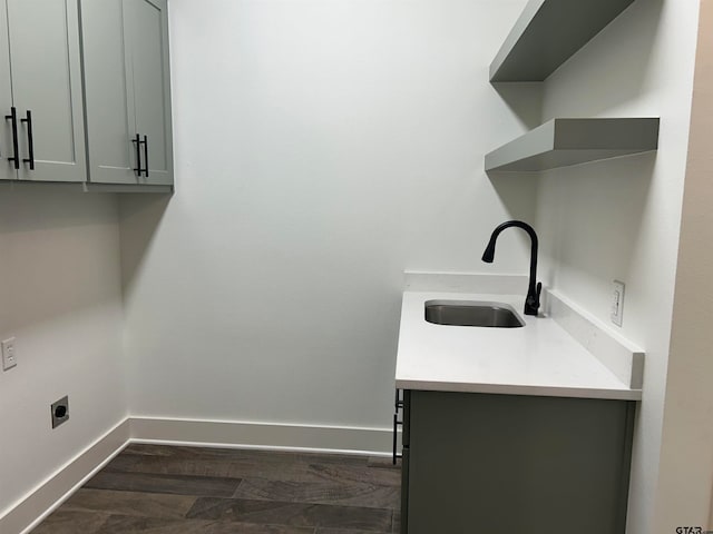 laundry area featuring dark wood-type flooring, cabinets, sink, and electric dryer hookup