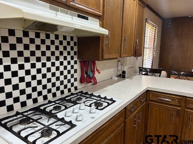 kitchen featuring white gas cooktop, decorative backsplash, and a breakfast bar area