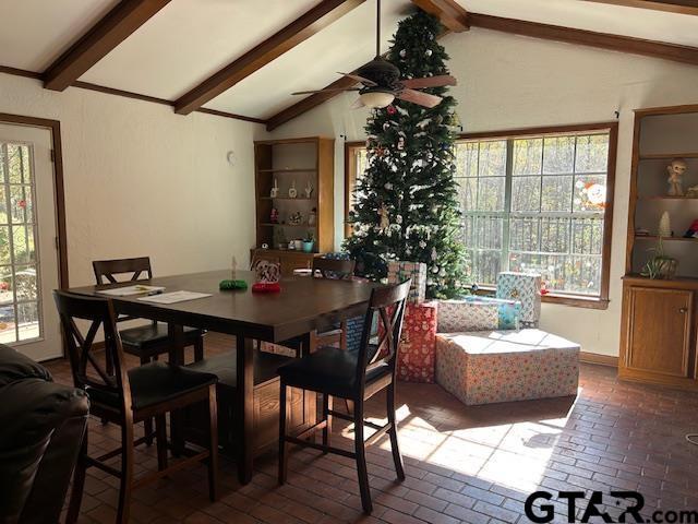 dining room with vaulted ceiling with beams, brick floor, plenty of natural light, and a ceiling fan