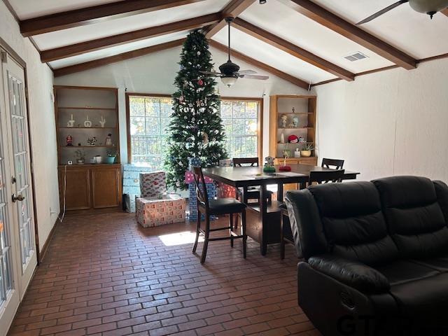 dining room with ceiling fan, lofted ceiling with beams, brick floor, and visible vents