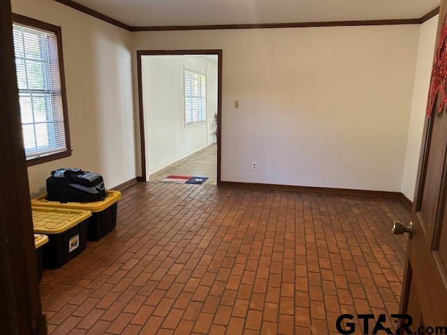 unfurnished room featuring brick floor and baseboards