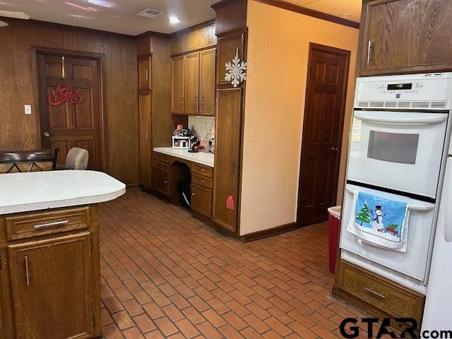 kitchen featuring white double oven, brick floor, visible vents, light countertops, and built in desk