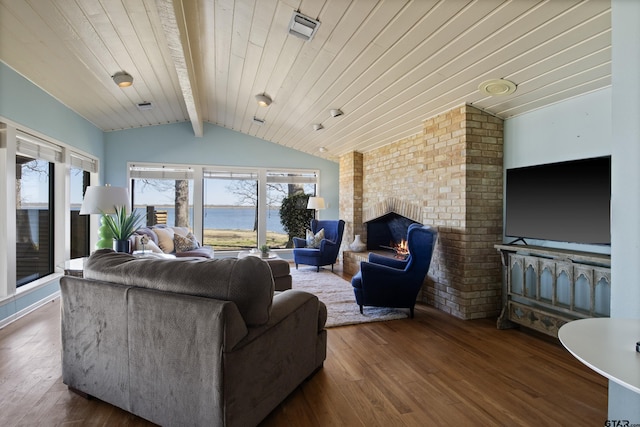 living area with a healthy amount of sunlight, a fireplace, lofted ceiling with beams, and wood finished floors