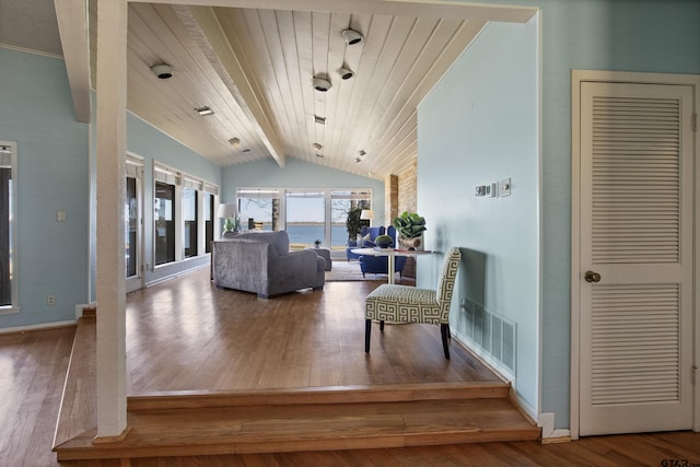 living area featuring visible vents, wood-type flooring, baseboards, and vaulted ceiling with beams