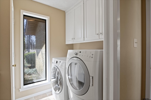 washroom featuring cabinet space and washer and clothes dryer