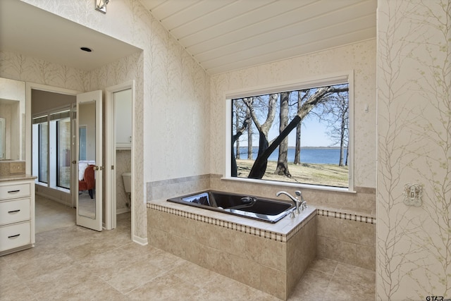 full bathroom with wallpapered walls, a garden tub, and a water view