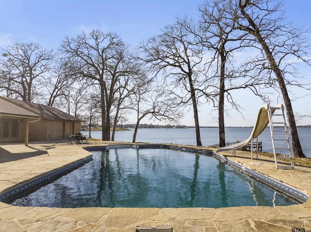 outdoor pool with a patio, a water view, and a water slide