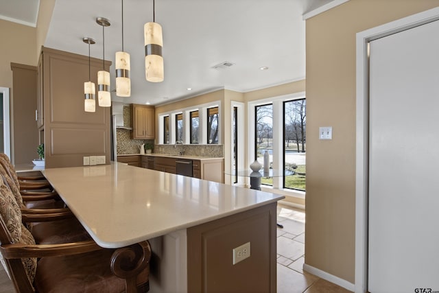 kitchen with a breakfast bar area, visible vents, a sink, decorative backsplash, and light countertops