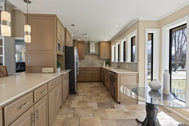 kitchen featuring a sink, wall chimney range hood, stainless steel appliances, light countertops, and decorative backsplash