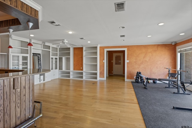 workout area featuring light wood-style floors, visible vents, and ceiling fan
