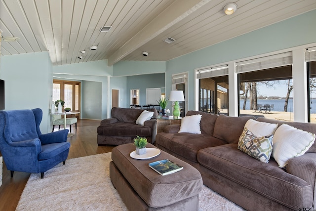 living area featuring visible vents, a water view, wood finished floors, and vaulted ceiling with beams