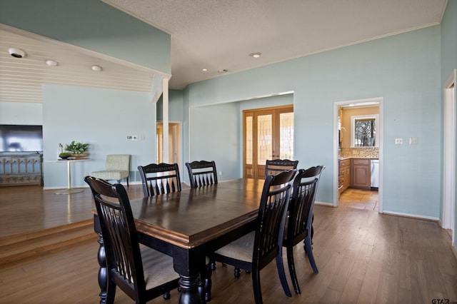 dining area with french doors, baseboards, and wood finished floors