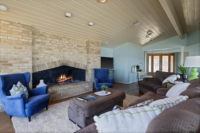 living room featuring visible vents, lofted ceiling with beams, wood finished floors, wooden ceiling, and a brick fireplace