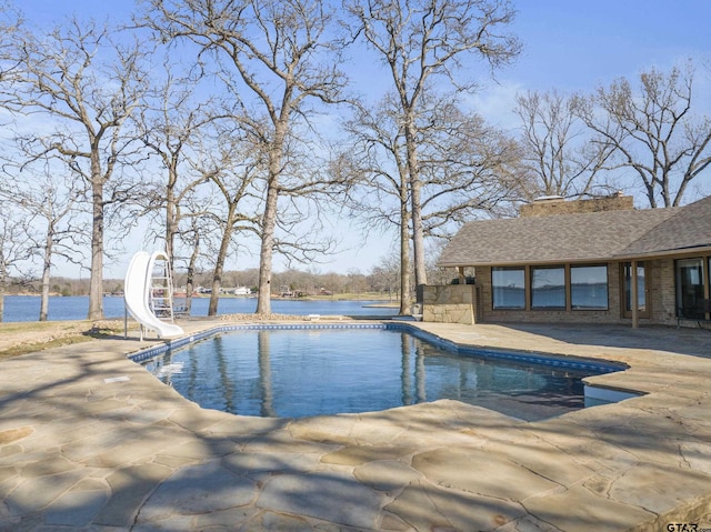 pool featuring a water slide, a patio, and a water view