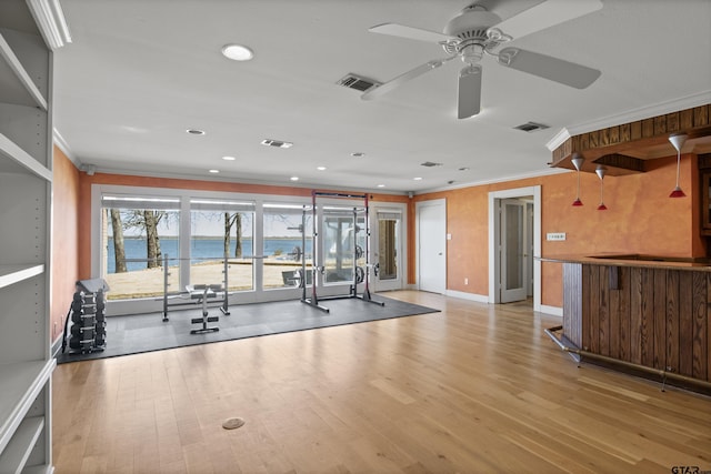 gym featuring visible vents, light wood-style floors, crown molding, and a ceiling fan