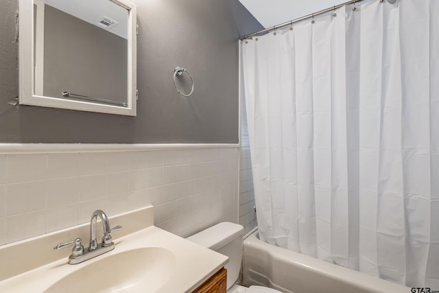 full bathroom featuring tile walls, vanity, toilet, and shower / tub combo