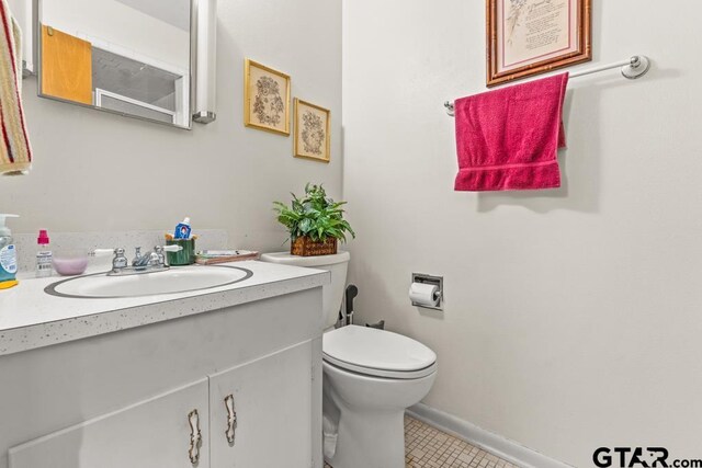 bathroom with toilet, baseboards, vanity, and tile patterned floors