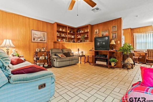 living area featuring brick floor, visible vents, ceiling fan, and wooden walls