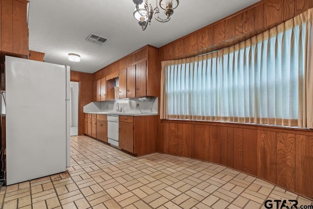 901 Dogwood St, Gilmer, TX 75644 - kitchen featuring white appliances, brown cabinets, wood walls, light countertops, and brick patterned flooring