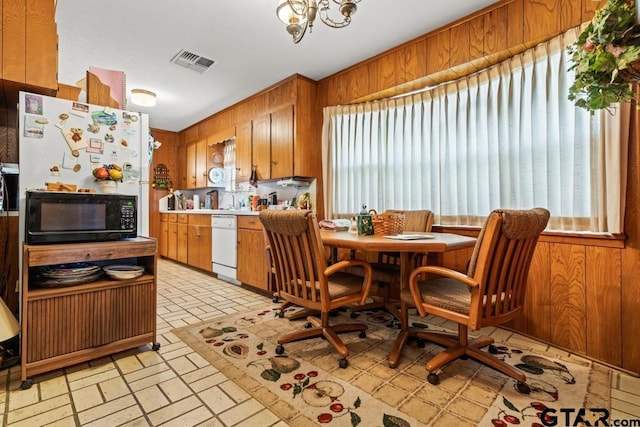 kitchen with black microwave, visible vents, and wooden walls