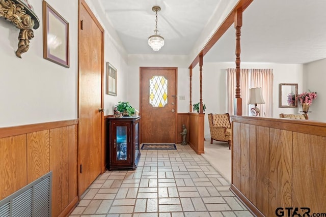 interior space featuring a wainscoted wall, wooden walls, visible vents, and brick floor