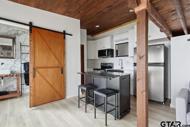 11020 Kevin Dr, Frankston, TX 75763 - kitchen featuring stainless steel appliances, wood ceiling, light wood-style flooring, a barn door, and a kitchen bar