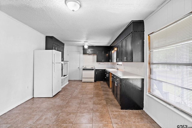 kitchen with a textured ceiling, a sink, dark cabinetry, and white appliances
