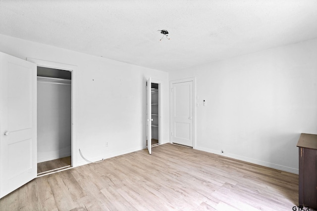 unfurnished bedroom with two closets, baseboards, and wood finished floors