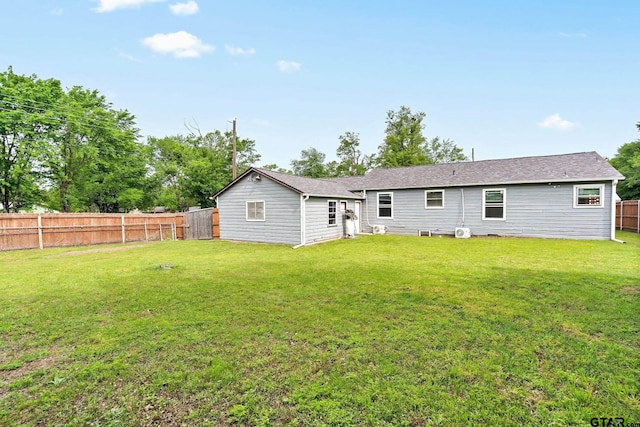 rear view of house featuring a lawn and a fenced backyard