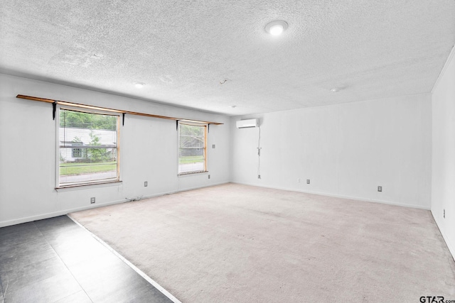 spare room featuring a wealth of natural light, an AC wall unit, a textured ceiling, and carpet