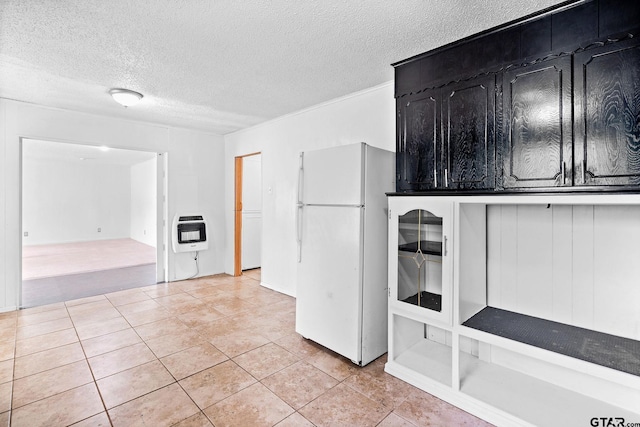 kitchen featuring heating unit, a textured ceiling, light tile patterned floors, dark cabinetry, and freestanding refrigerator