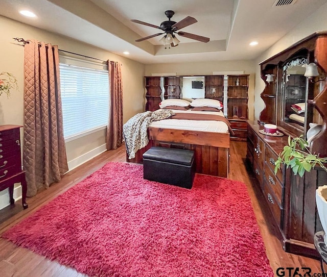 bedroom featuring hardwood / wood-style flooring, ceiling fan, and a raised ceiling