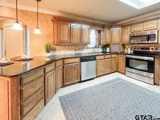 kitchen featuring light tile patterned flooring, appliances with stainless steel finishes, decorative light fixtures, sink, and dark stone countertops