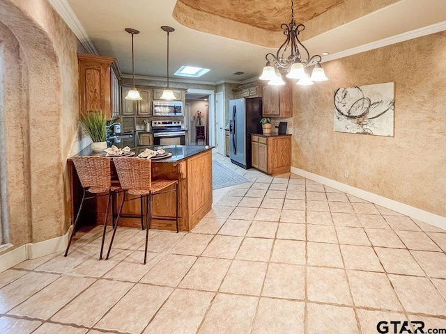 kitchen with appliances with stainless steel finishes, a raised ceiling, pendant lighting, a breakfast bar area, and kitchen peninsula