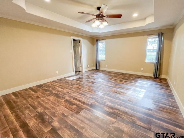 spare room featuring crown molding, dark wood-type flooring, ceiling fan, and a raised ceiling