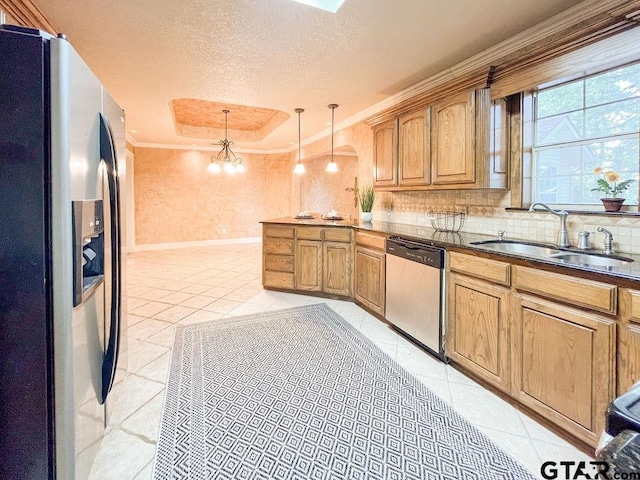 kitchen featuring ornamental molding, appliances with stainless steel finishes, decorative light fixtures, a textured ceiling, and sink